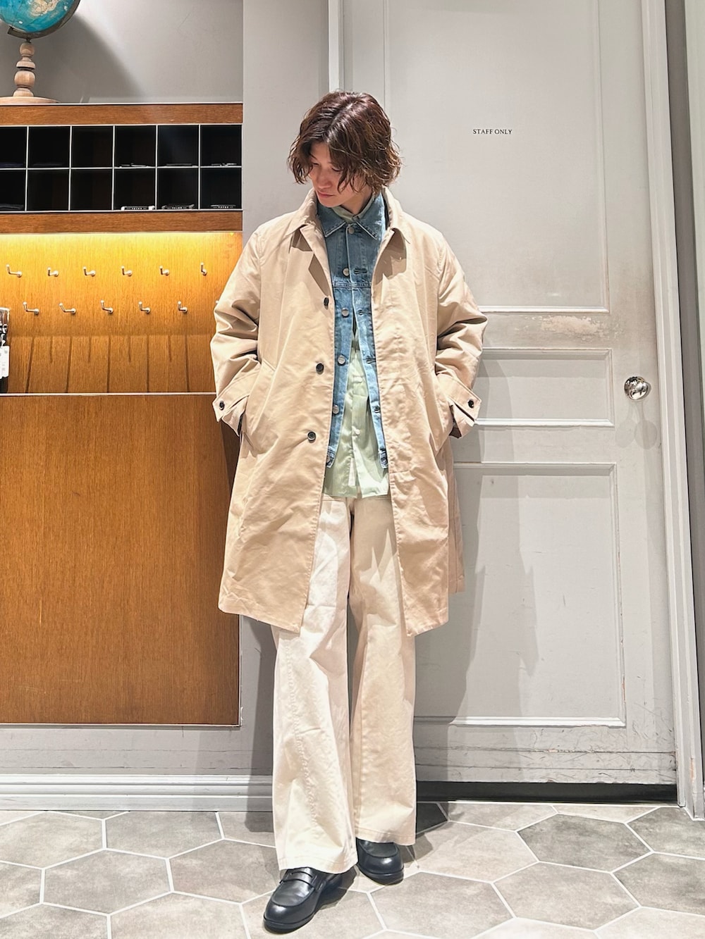 ベージュ系のステンカラーコート、ホワイト系のチノパンツ、ブラック系のローファーを着用したメンズの春コーディネートの2枚目の写真