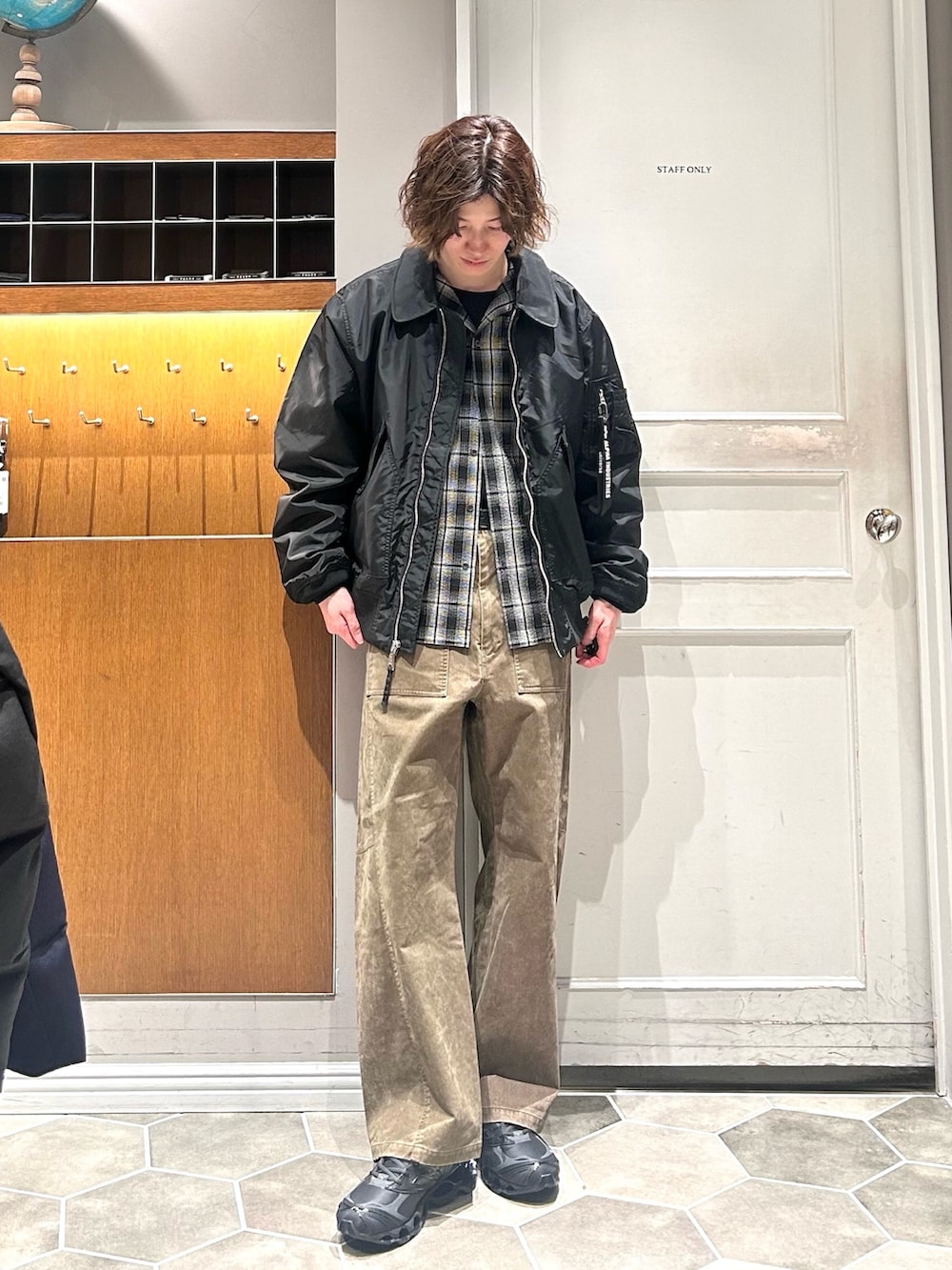 ブラック系のブルゾン、グリーン系のチノパンツ、ブラック系のスニーカーを着用したメンズの春コーディネートの2枚目の写真