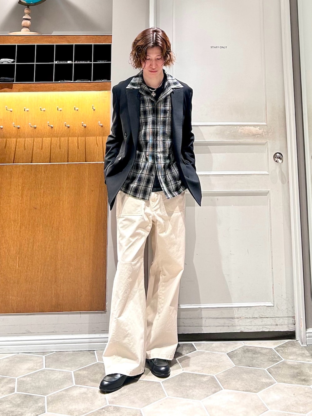 ブラック系のテーラードジャケット、ホワイト系のチノパンツを着用したメンズの春コーディネートの2枚目の写真