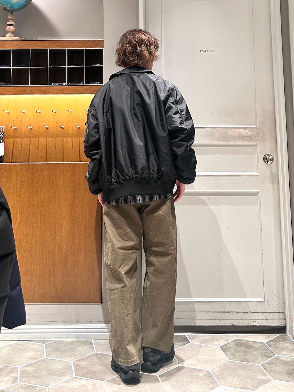 ブラック系のブルゾン、グリーン系のチノパンツ、ブラック系のスニーカーを着用したメンズの春コーディネートの4枚目の写真