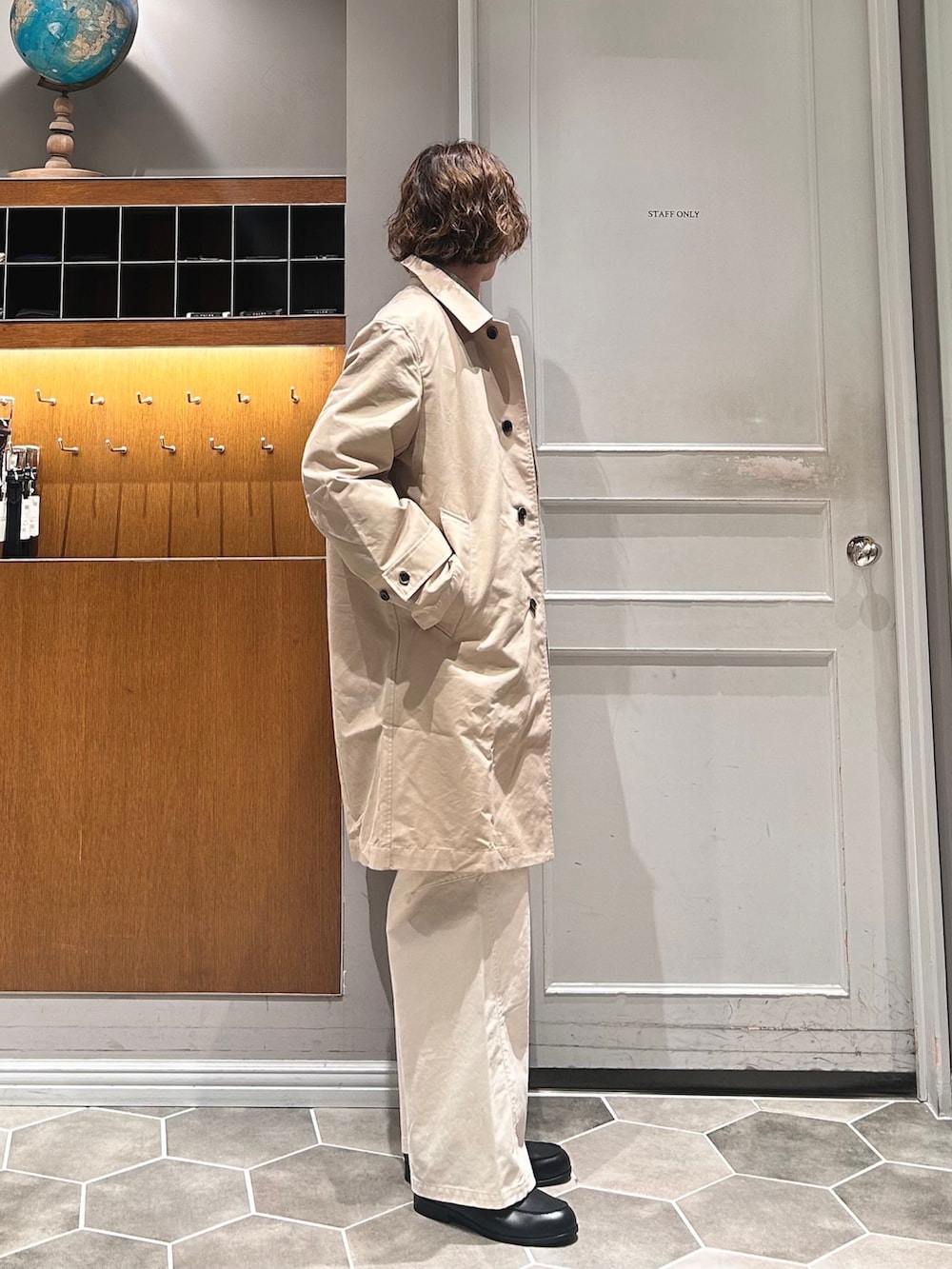 ベージュ系のステンカラーコート、ホワイト系のチノパンツ、ブラック系のローファーを着用したメンズの春コーディネートの3枚目の写真