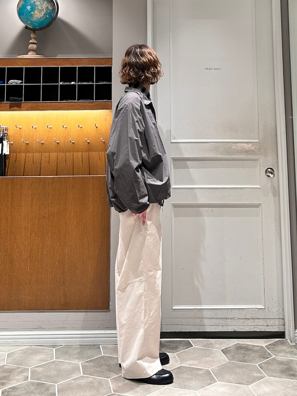 グレー系のナイロンジャケット、ホワイト系のチノパンツ、ブラック系のローファーを着用したメンズの春コーディネートの2枚目の写真