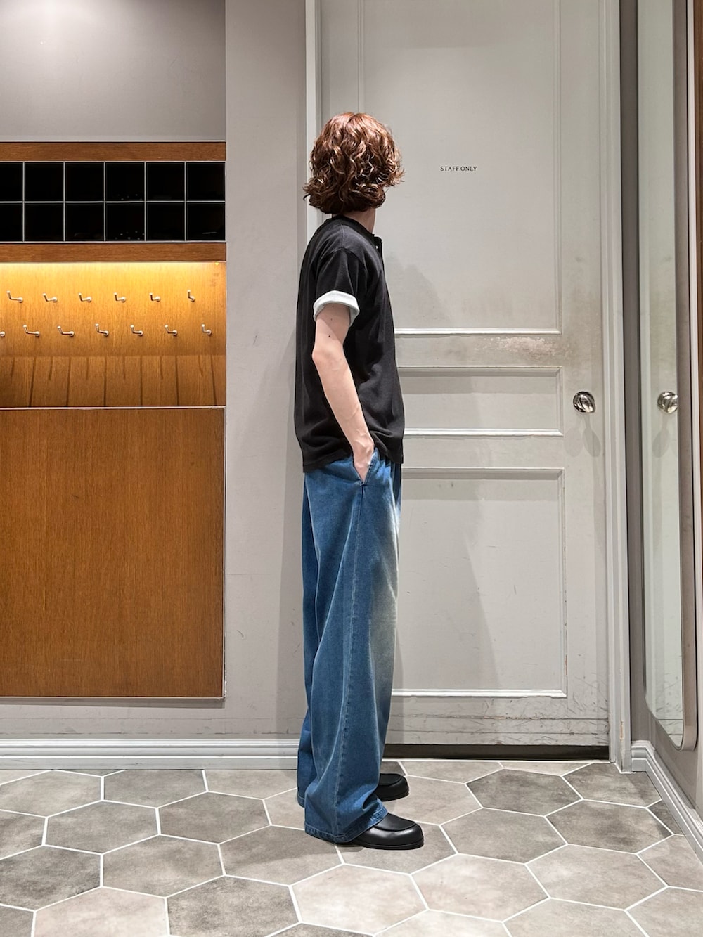 ブルー系のデニムパンツ、ブラック系のTシャツ/カットソー、ブラック系のローファーを着用したメンズの秋コーディネートの2枚目の写真