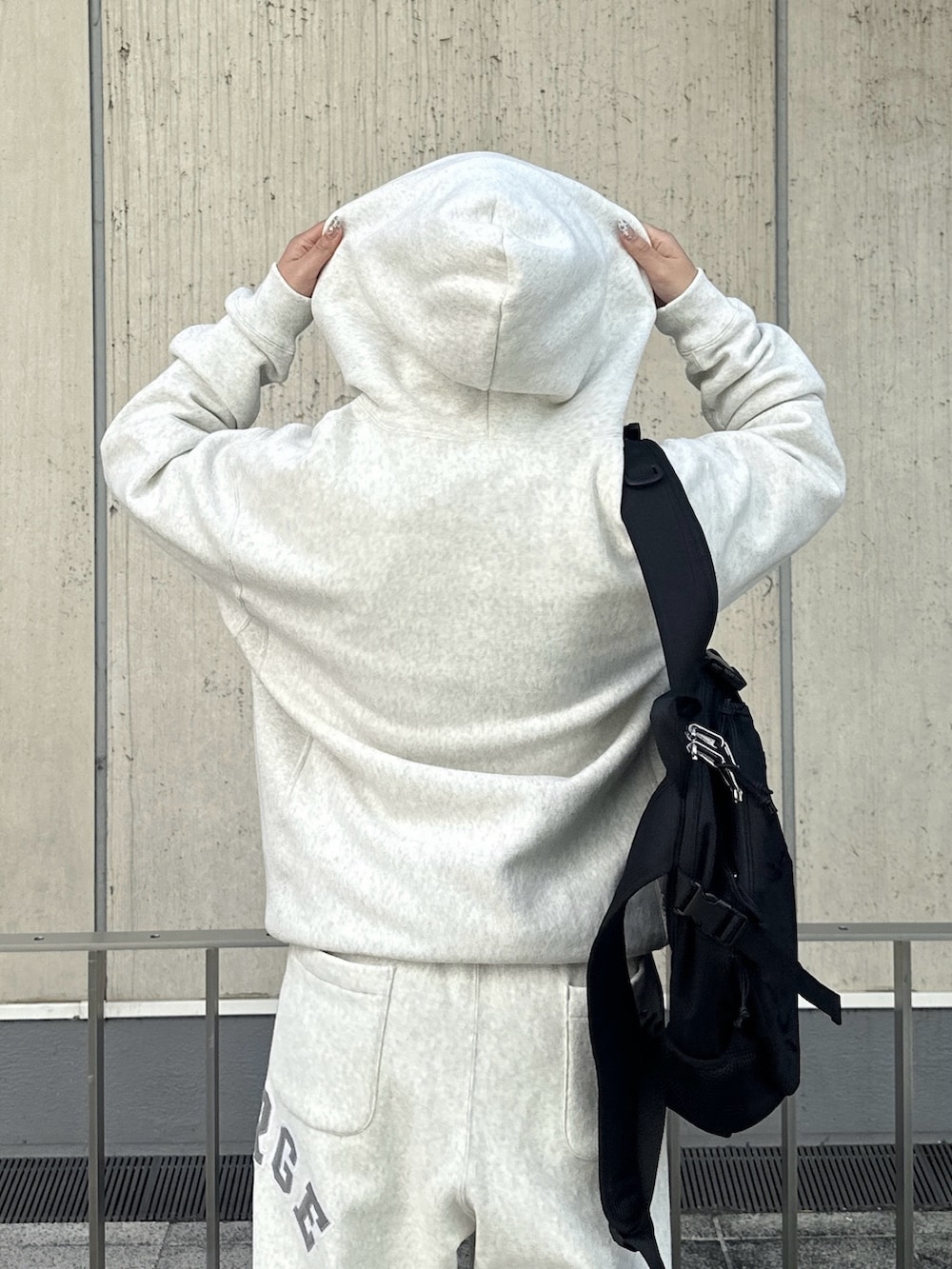 グレー系のパーカー、グレー系のスウェットパンツ、ブラック系のバックパック/リュックを着用したレディースの秋コーディネートの4枚目の写真