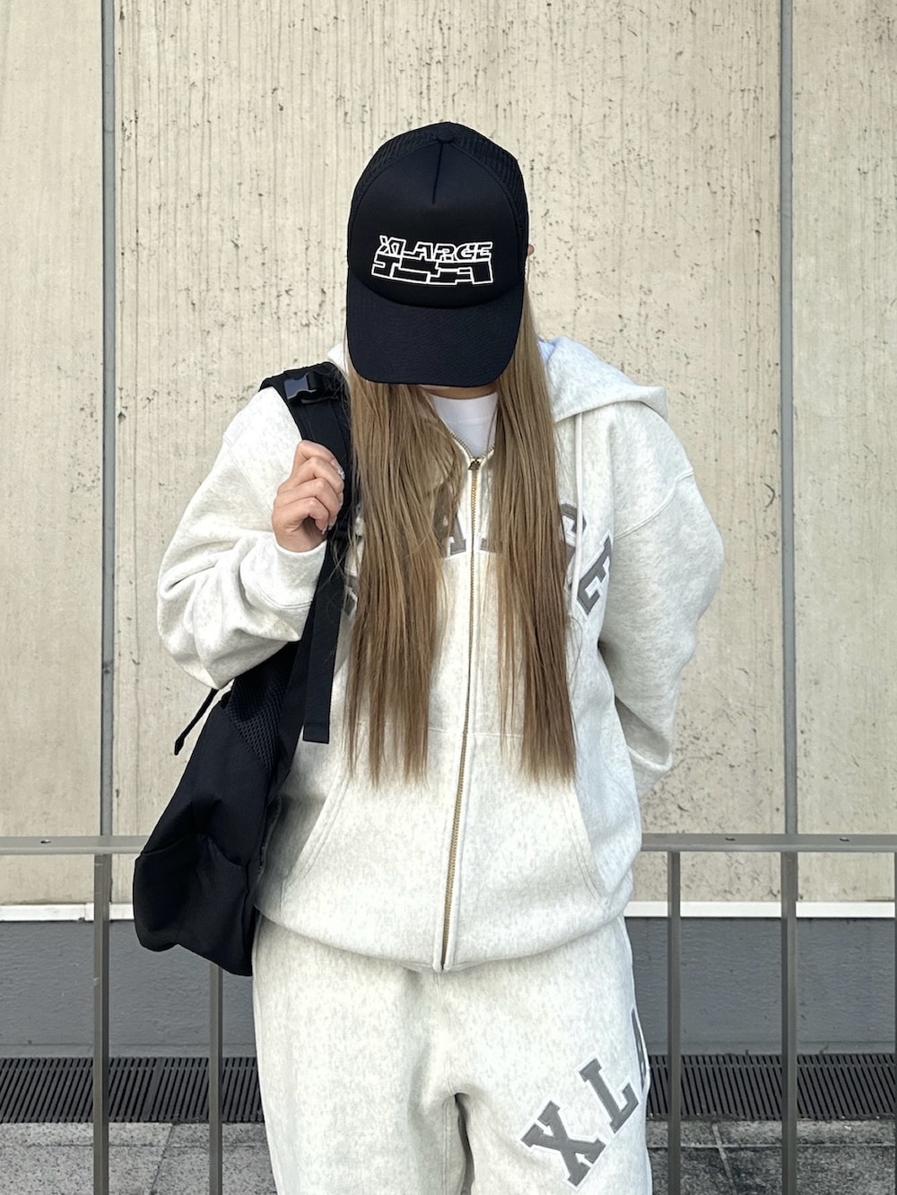 グレー系のパーカー、グレー系のスウェットパンツ、ブラック系のバックパック/リュックを着用したレディースの秋コーディネートの3枚目の写真