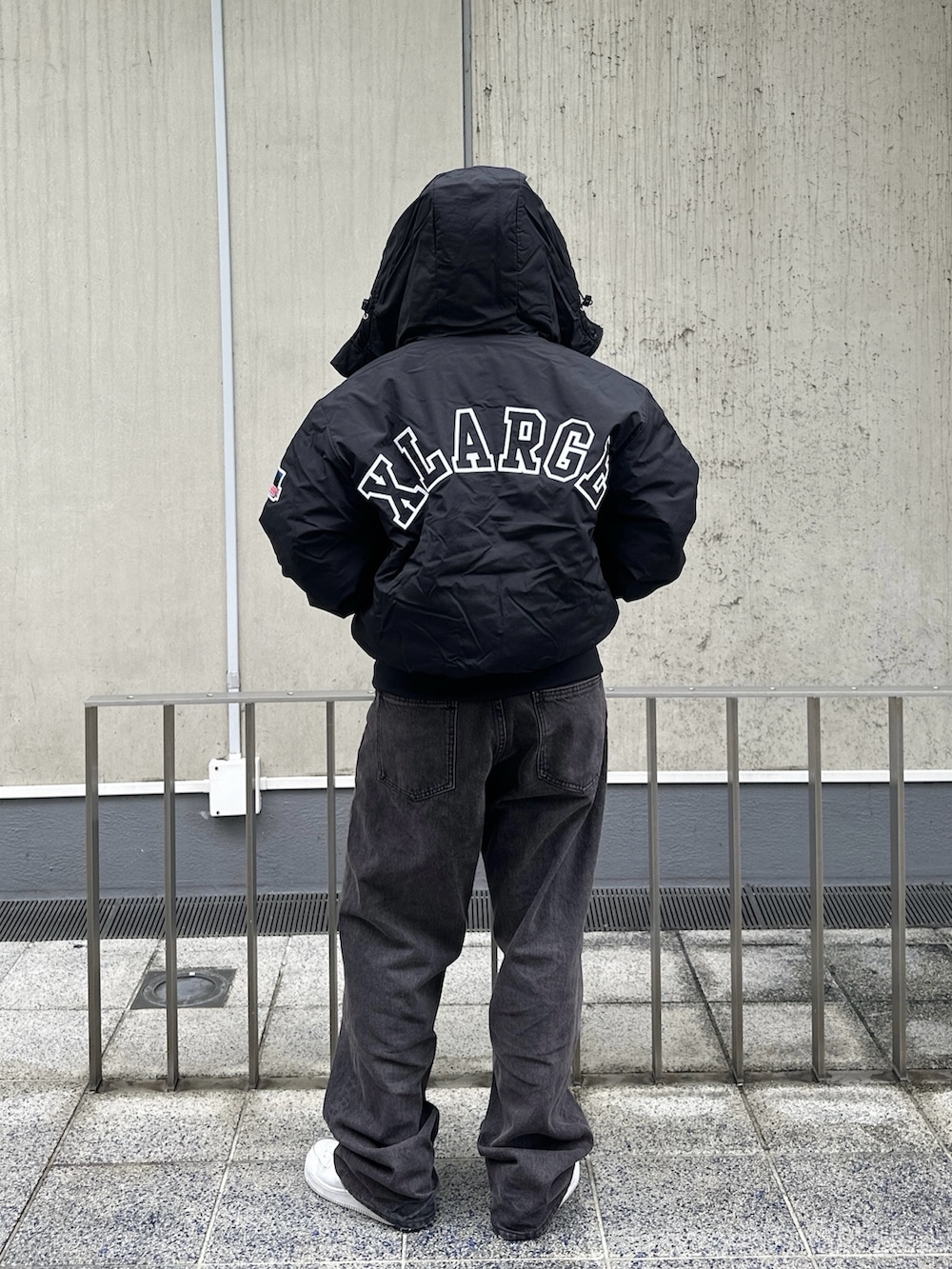 ホワイト系のパーカー、ブラック系のブルゾン、ブラウン系のデニムパンツを着用したレディースの秋コーディネートの4枚目の写真