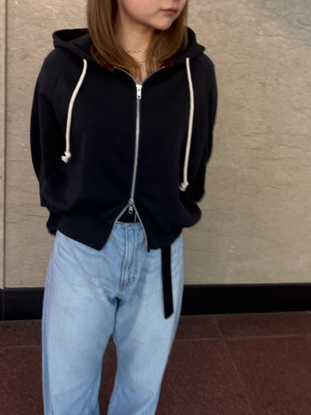 ブルー系のデニムパンツ、グレー系のパーカーを着用したレディースの春コーディネートの4枚目の写真