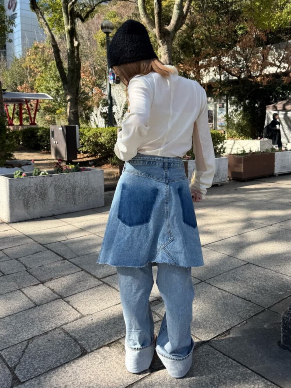 ブルー系のスカート、ホワイト系のTシャツ/カットソー、ブラウン系のブルゾンを着用したレディースの冬コーディネートの5枚目の写真