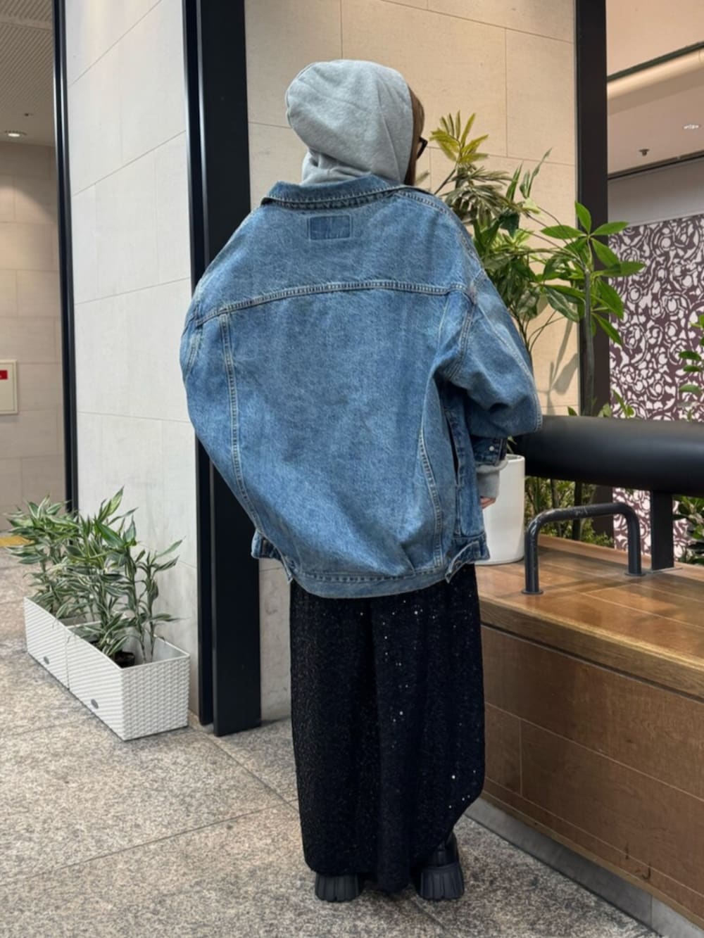 グレー系のパーカー、ブルー系のデニムジャケット、ブラック系のスカートを着用したレディースの春コーディネートの3枚目の写真