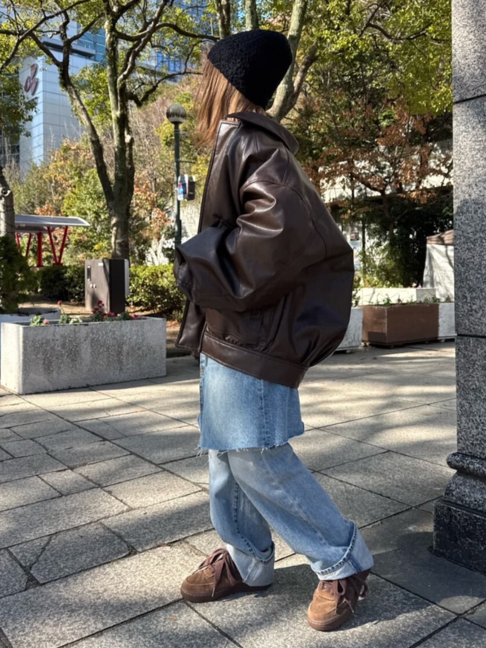 ブルー系のスカート、ホワイト系のTシャツ/カットソー、ブラウン系のブルゾンを着用したレディースの冬コーディネートの2枚目の写真