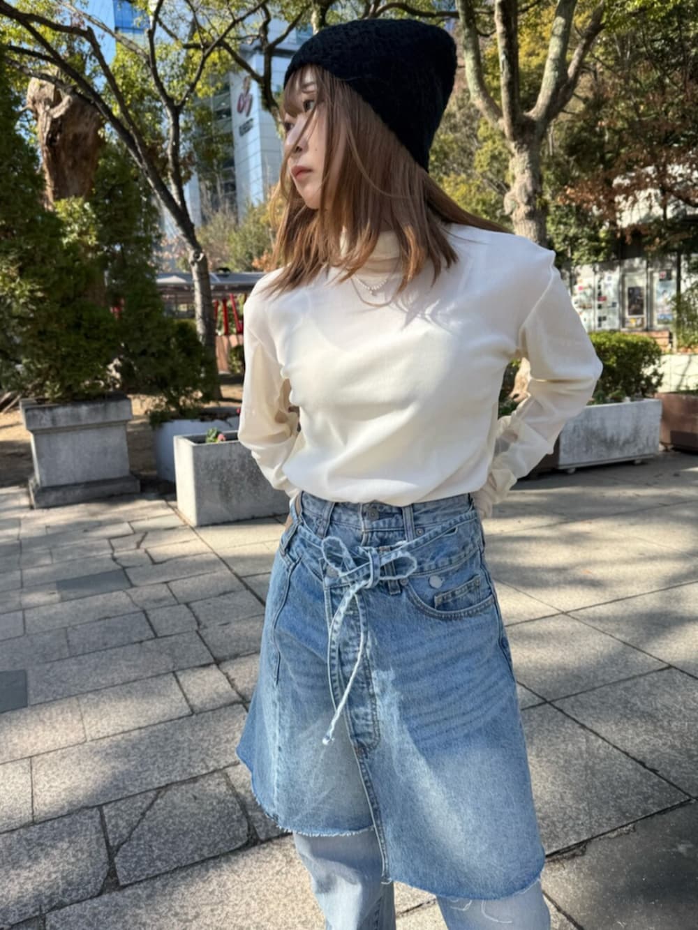 ブルー系のスカート、ホワイト系のTシャツ/カットソー、ブラウン系のブルゾンを着用したレディースの冬コーディネートの4枚目の写真