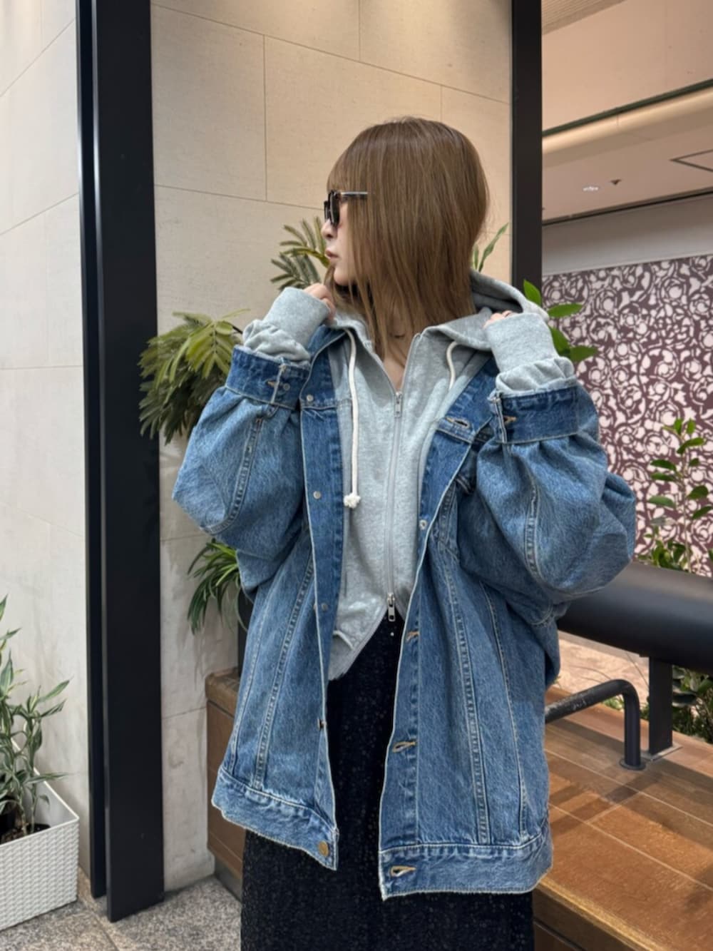 グレー系のパーカー、ブルー系のデニムジャケット、ブラック系のスカートを着用したレディースの春コーディネートの4枚目の写真