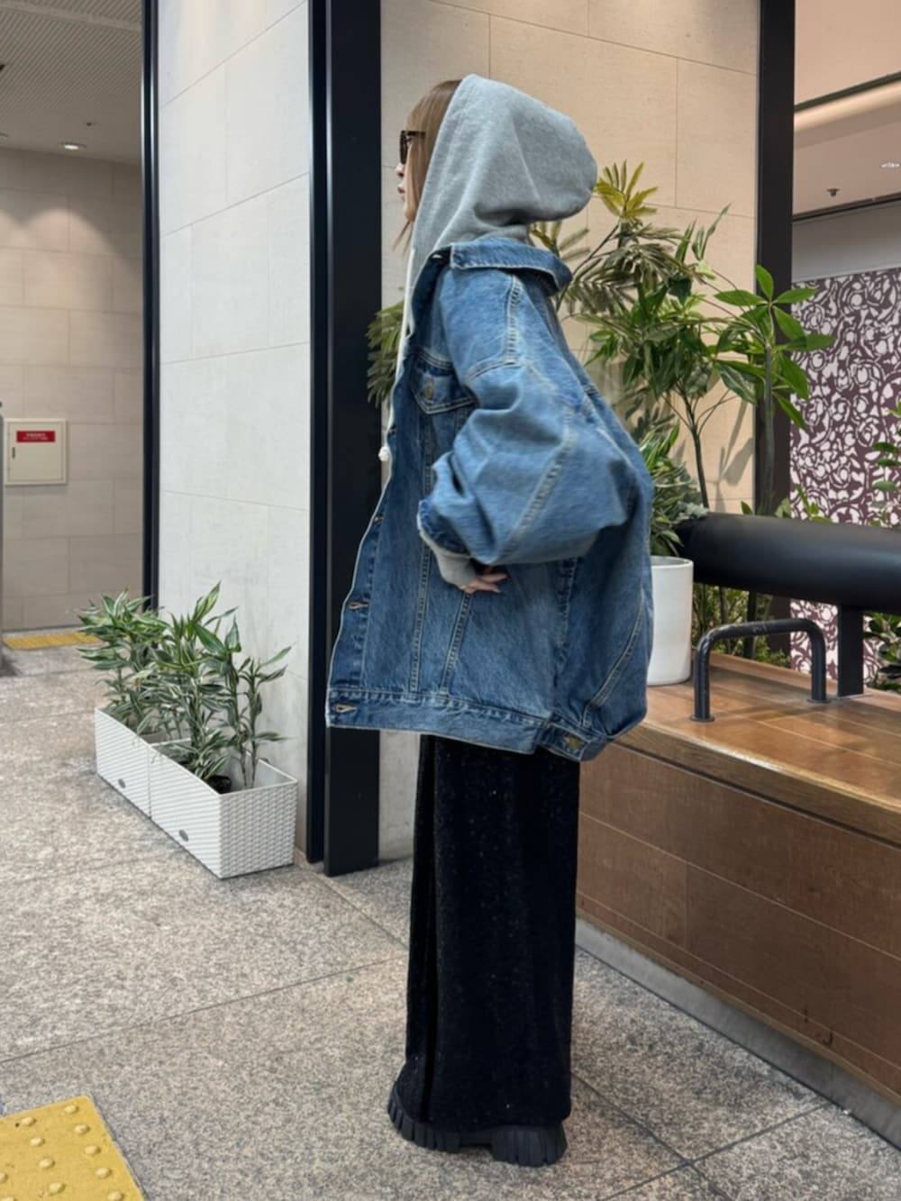 グレー系のパーカー、ブルー系のデニムジャケット、ブラック系のスカートを着用したレディースの春コーディネートの2枚目の写真