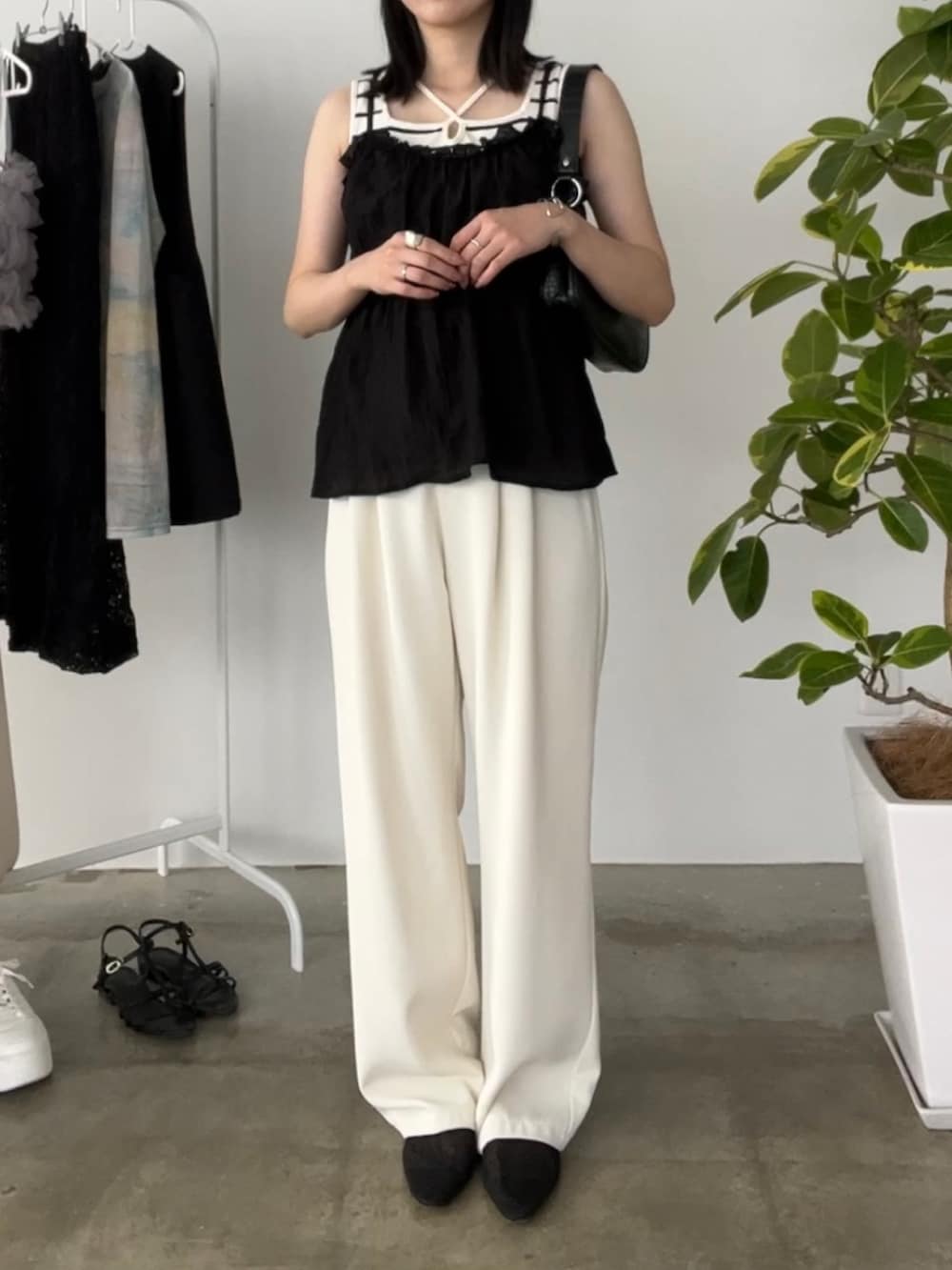 ホワイト系のスラックス、ホワイト系のタンクトップ、ブラック系のトップスを着用したレディースの夏コーディネートの3枚目の写真