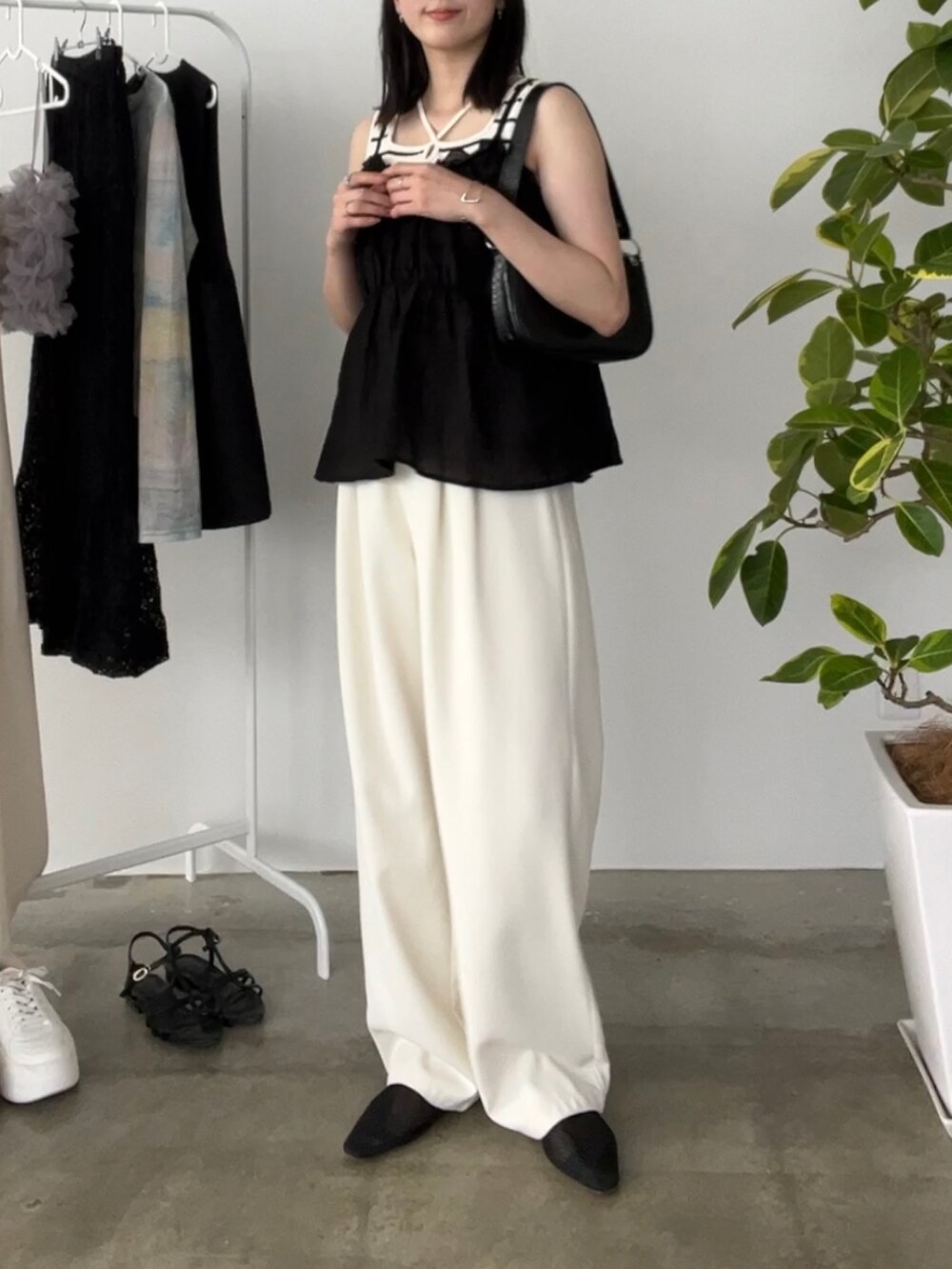ホワイト系のスラックス、ホワイト系のタンクトップ、ブラック系のトップスを着用したレディースの夏コーディネートの2枚目の写真