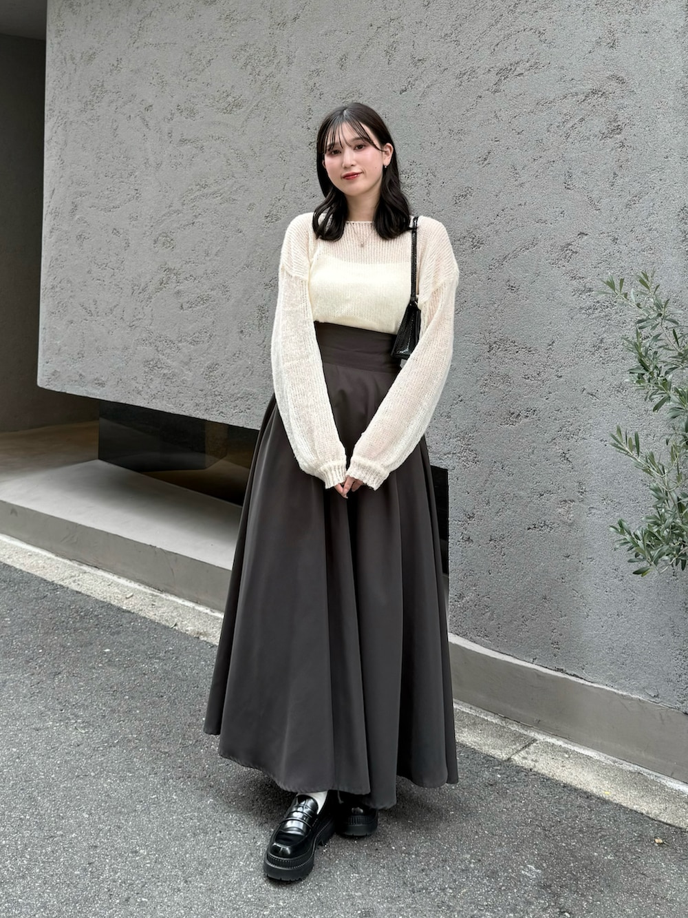 ホワイト系のニット/セーター、グレー系のスカート、ブラック系のローファーを着用したレディースの秋コーディネートの2枚目の写真