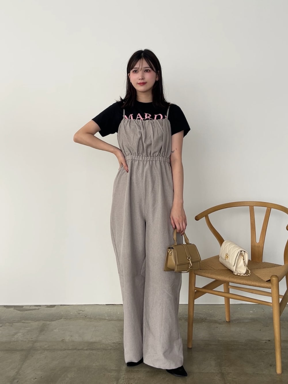 ブラック系のTシャツ/カットソー、ベージュ系のサロペット/オーバーオール、ブラック系のパンプスを着用したレディースの秋コーディネートの2枚目の写真