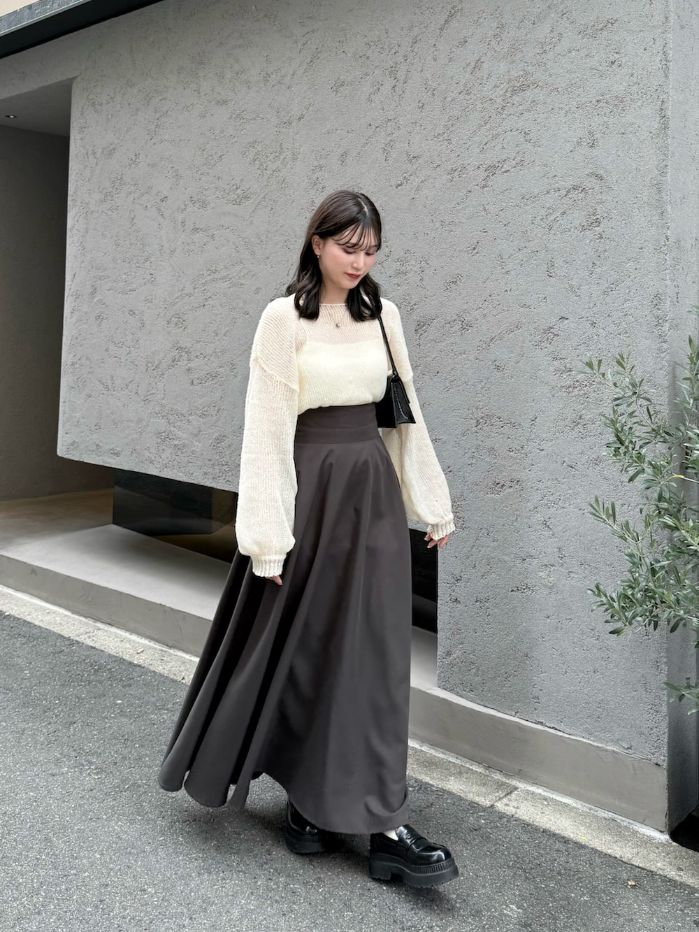 ホワイト系のニット/セーター、グレー系のスカート、ブラック系のローファーを着用したレディースの秋コーディネートの3枚目の写真