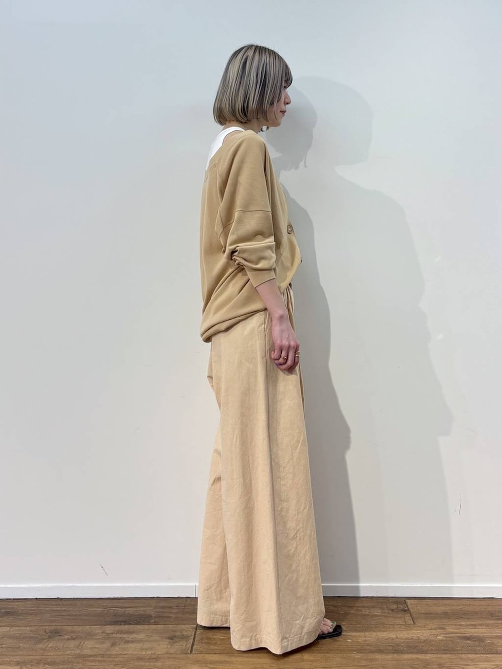 ホワイト系のアンサンブル、ベージュ系のカーディガン/ボレロ、ベージュ系のその他パンツを着用したレディースの春コーディネートの2枚目の写真