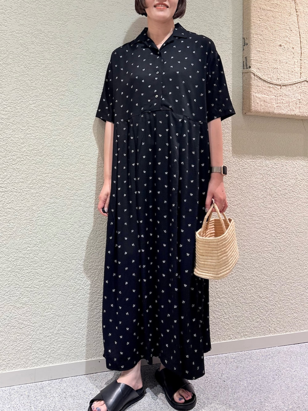 ブラック系のワンピース、ベージュ系のかごバッグ、ブラック系のサンダルを着用したレディースの夏コーディネートの6枚目の写真