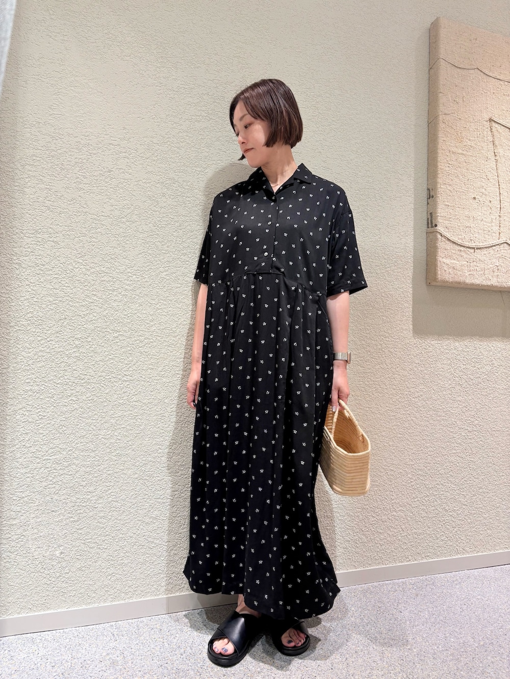 ブラック系のワンピース、ベージュ系のかごバッグ、ブラック系のサンダルを着用したレディースの夏コーディネートの3枚目の写真