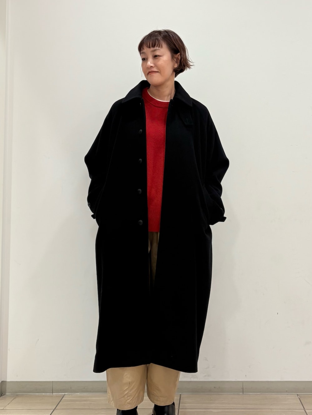 ブラック系のステンカラーコート、パープル系のその他パンツ、レッド系のニット/セーターを着用したレディースの冬コーディネートの2枚目の写真