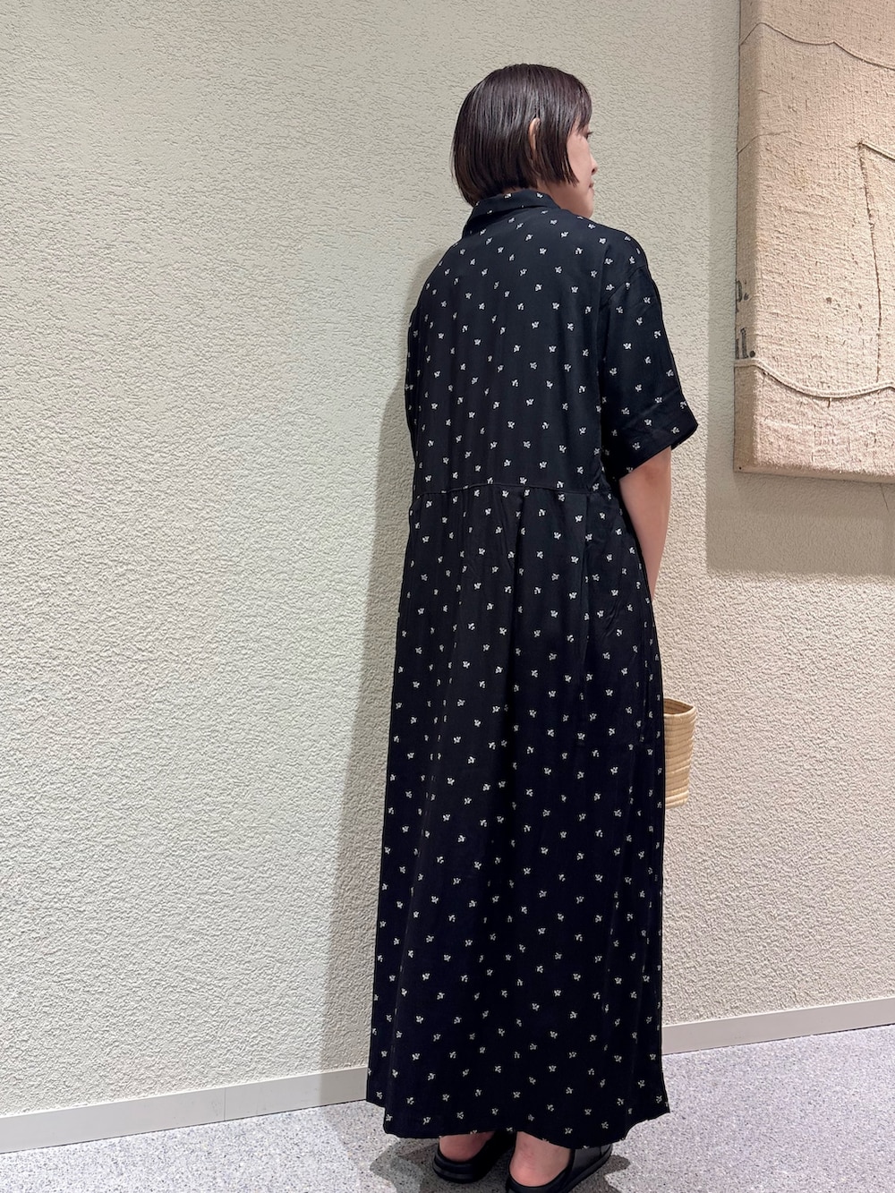 ブラック系のワンピース、ベージュ系のかごバッグ、ブラック系のサンダルを着用したレディースの夏コーディネートの5枚目の写真