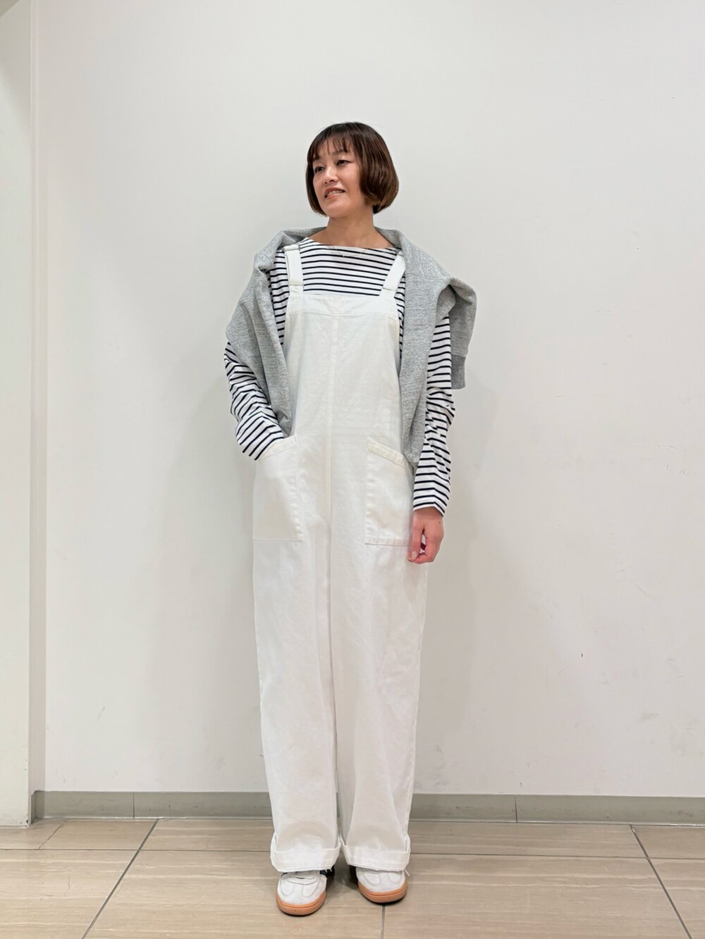 グレー系のスウェット、ホワイト系のサロペット/オーバーオール、ブラック系のTシャツ/カットソーを着用したレディースの冬コーディネートの2枚目の写真