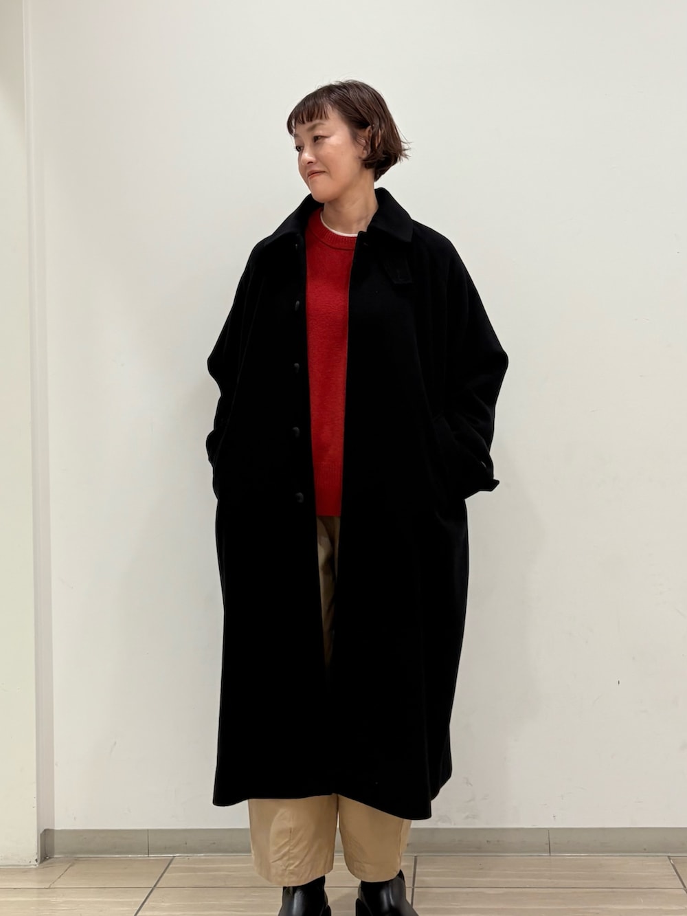 ブラック系のステンカラーコート、パープル系のその他パンツ、レッド系のニット/セーターを着用したレディースの冬コーディネートの3枚目の写真