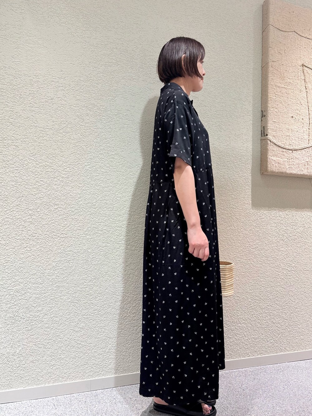 ブラック系のワンピース、ベージュ系のかごバッグ、ブラック系のサンダルを着用したレディースの夏コーディネートの4枚目の写真