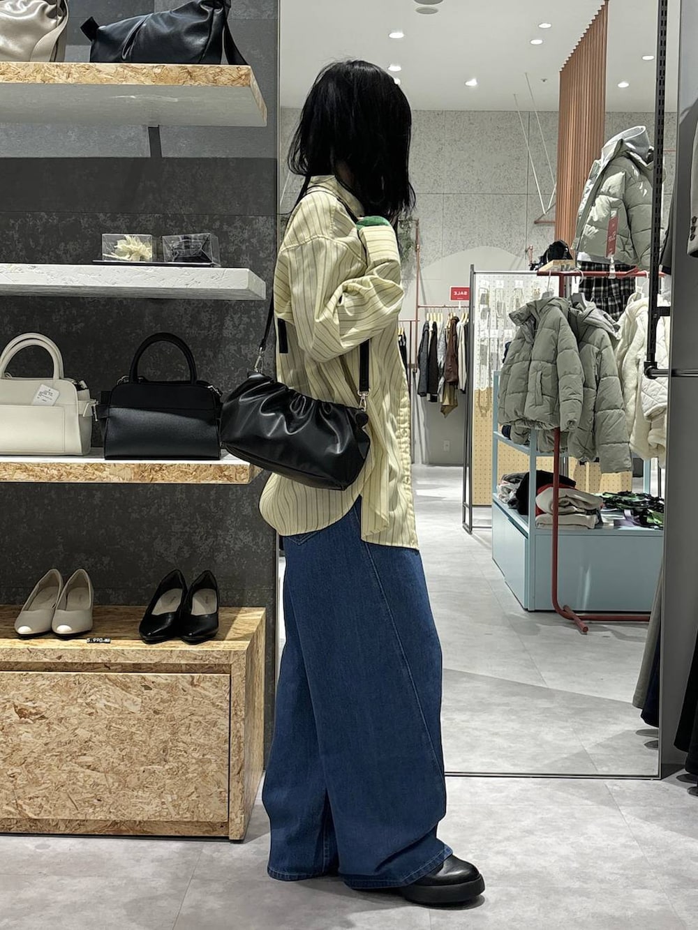 ブラック系のTシャツ/カットソー、ブラック系のショルダーバッグ、ブルー系のデニムパンツを着用したレディースの冬コーディネートの3枚目の写真