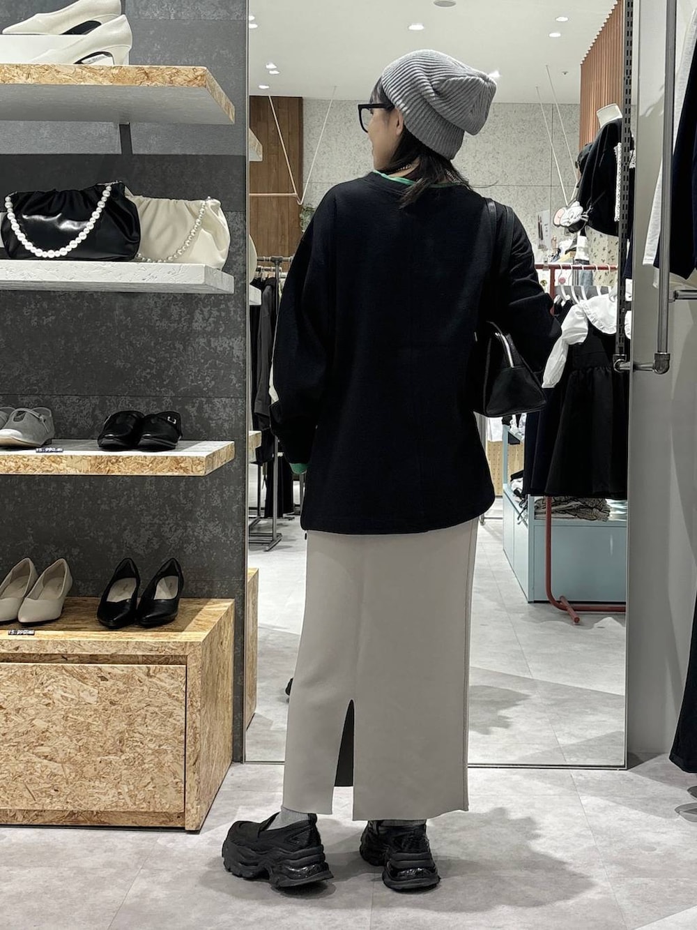 グレー系のスカート、ブラック系のローファー、ブラック系のボストンバッグを着用したレディースの冬コーディネートの4枚目の写真