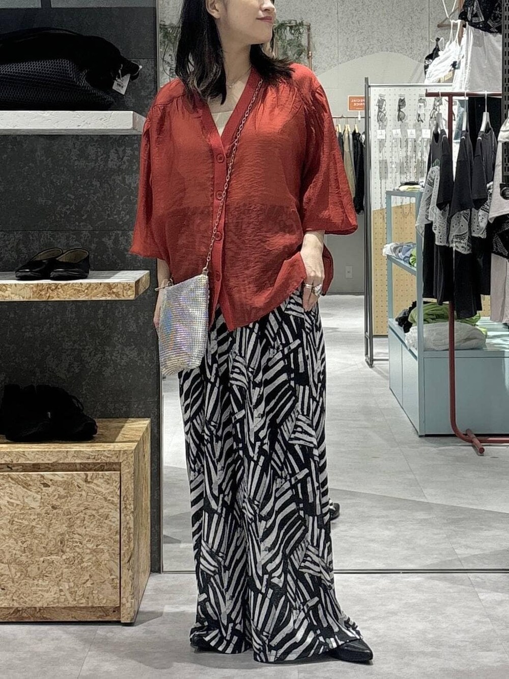 ブラック系のその他パンツ、レッド系のシャツ/ブラウス、シルバー系のショルダーバッグを着用したレディースの春コーディネートの2枚目の写真