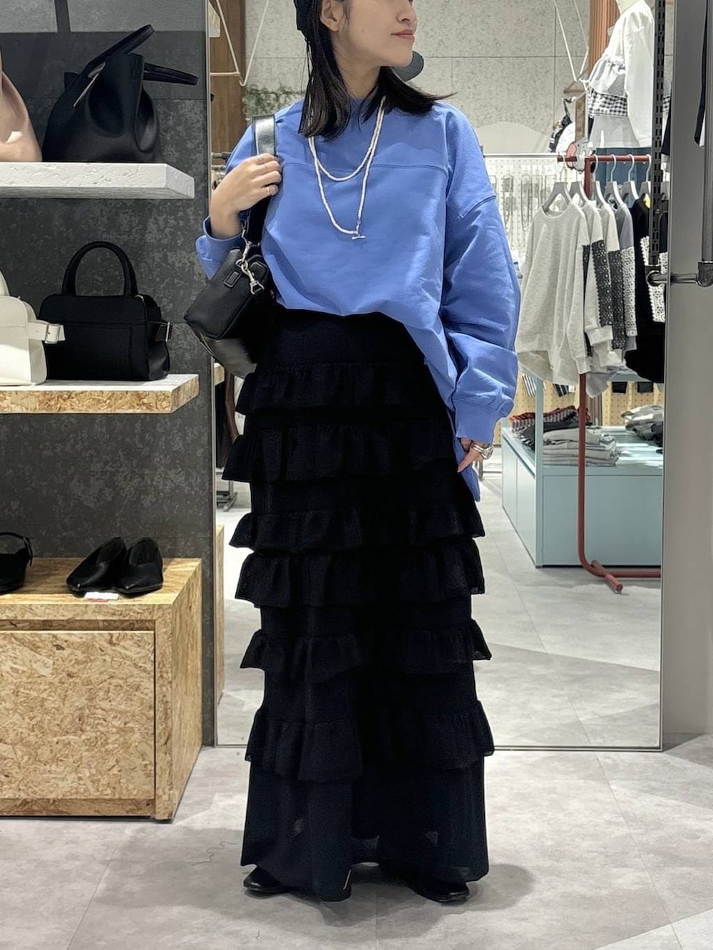 ブラック系のパンプス、ブルー系のTシャツ/カットソー、ブラック系のショルダーバッグを着用したレディースの春コーディネートの2枚目の写真