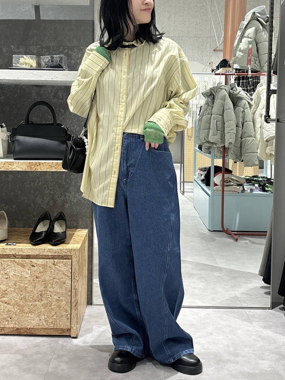 ブラック系のTシャツ/カットソー、ブラック系のショルダーバッグ、ブルー系のデニムパンツを着用したレディースの冬コーディネートの2枚目の写真