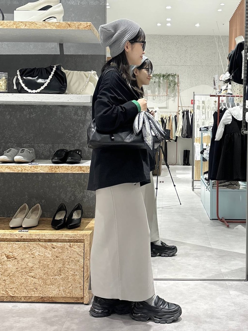 グレー系のスカート、ブラック系のローファー、ブラック系のボストンバッグを着用したレディースの冬コーディネートの5枚目の写真