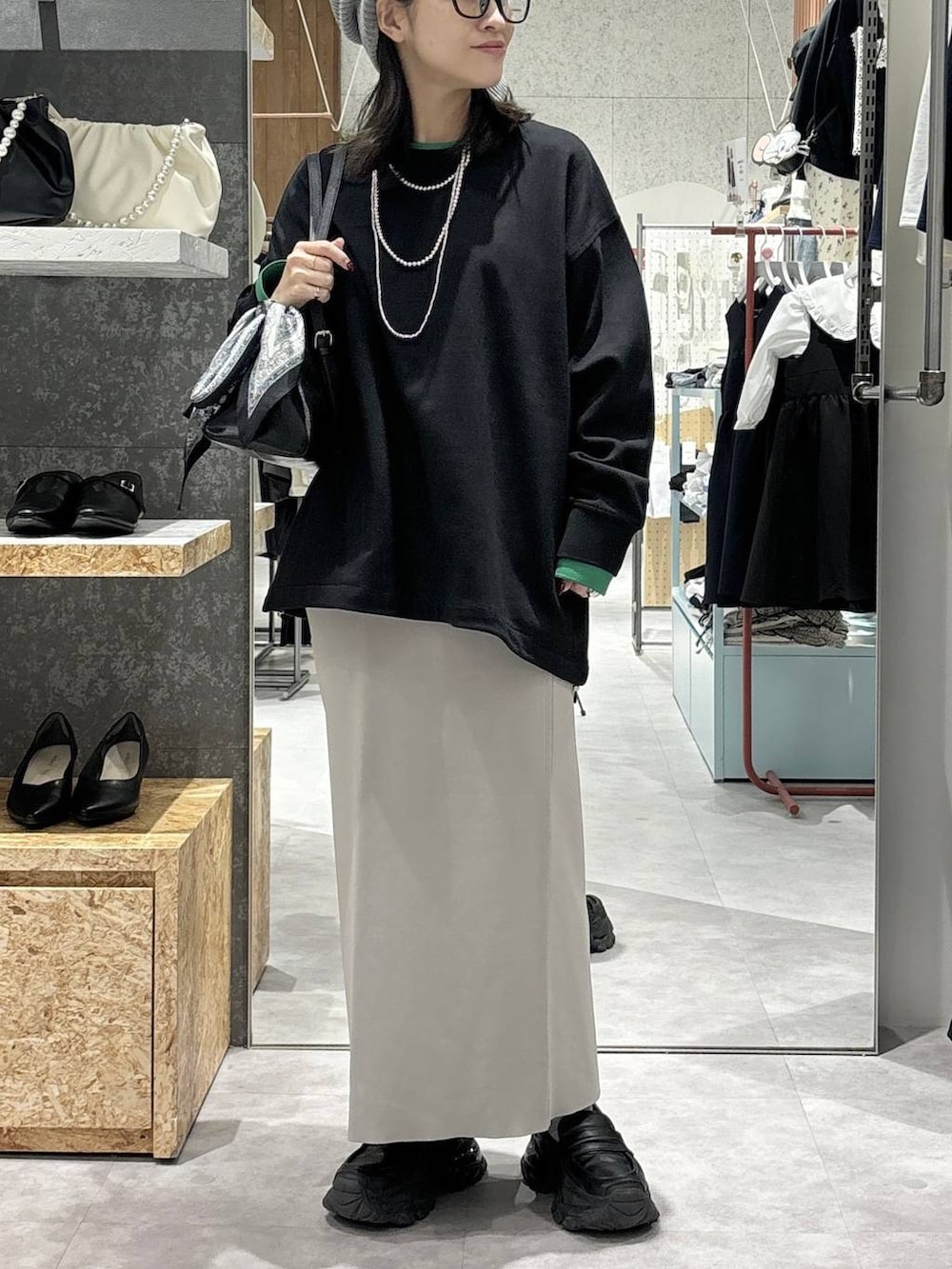 グレー系のスカート、ブラック系のローファー、ブラック系のボストンバッグを着用したレディースの冬コーディネートの2枚目の写真