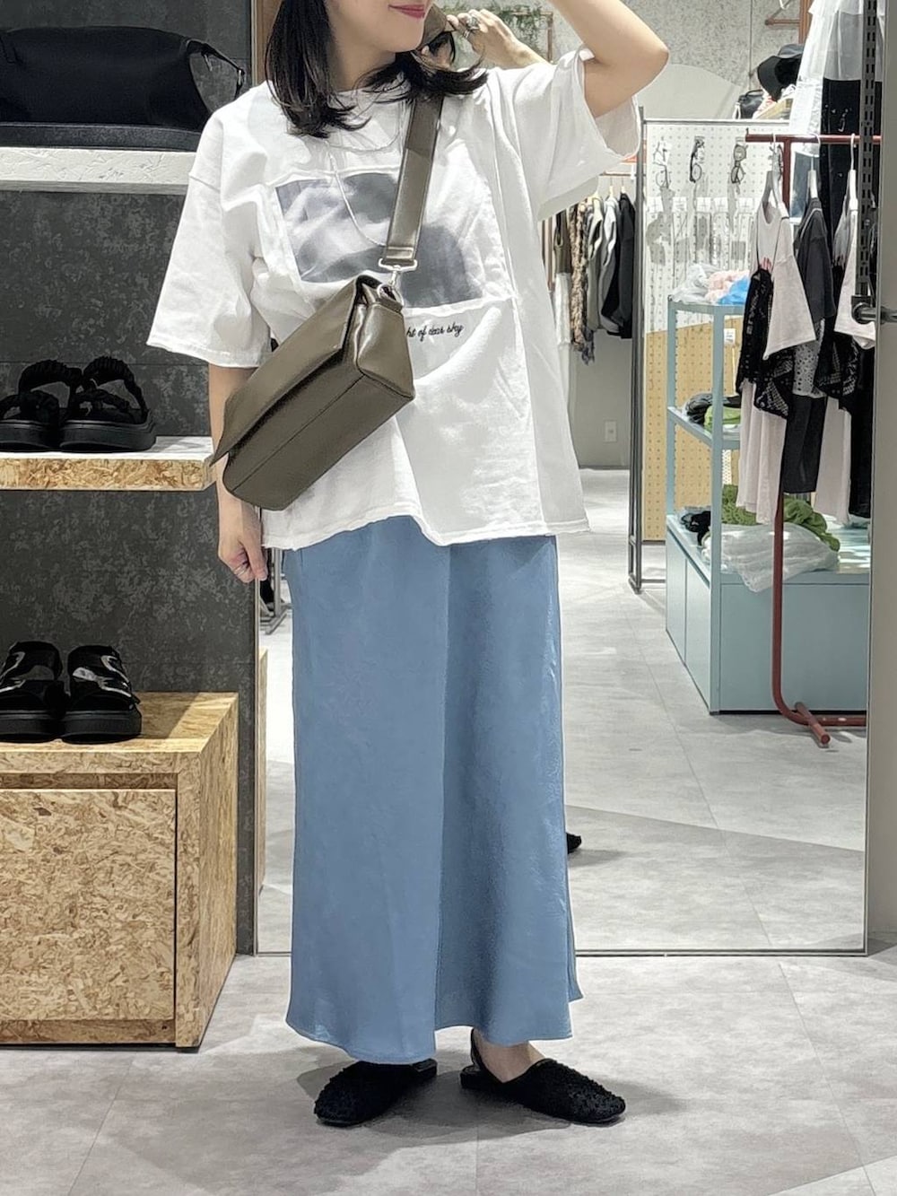 ブラウン系のショルダーバッグ、ブルー系のスカート、ブラック系のパンプスを着用したレディースの春コーディネートの2枚目の写真