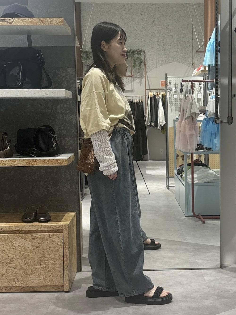 ブラック系のサンダル、ベージュ系のTシャツ/カットソー、ブラウン系のショルダーバッグを着用したレディースの春コーディネートの3枚目の写真