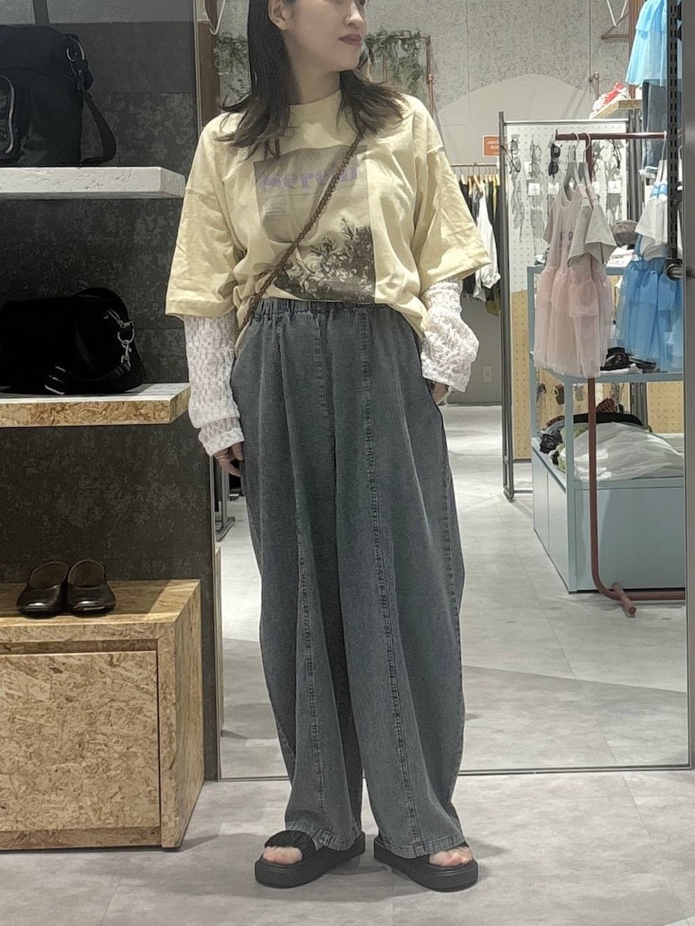 ブラック系のサンダル、ベージュ系のTシャツ/カットソー、ブラウン系のショルダーバッグを着用したレディースの春コーディネートの2枚目の写真