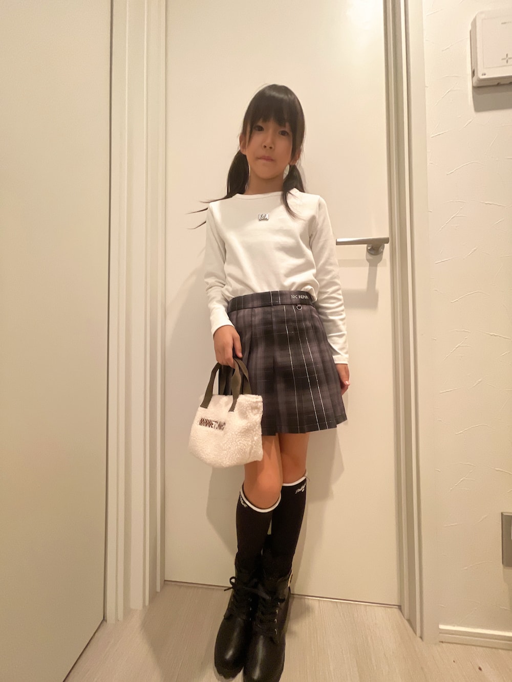 ホワイト系のトップス、ブラック系のスカート、ホワイト系のショルダーバッグを着用したキッズの秋コーディネートの3枚目の写真