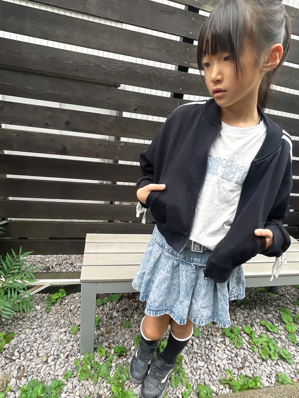 ブルー系のデニムスカート、ホワイト系のTシャツ/カットソー、ブラック系のセットアップを着用したキッズの秋コーディネートの3枚目の写真