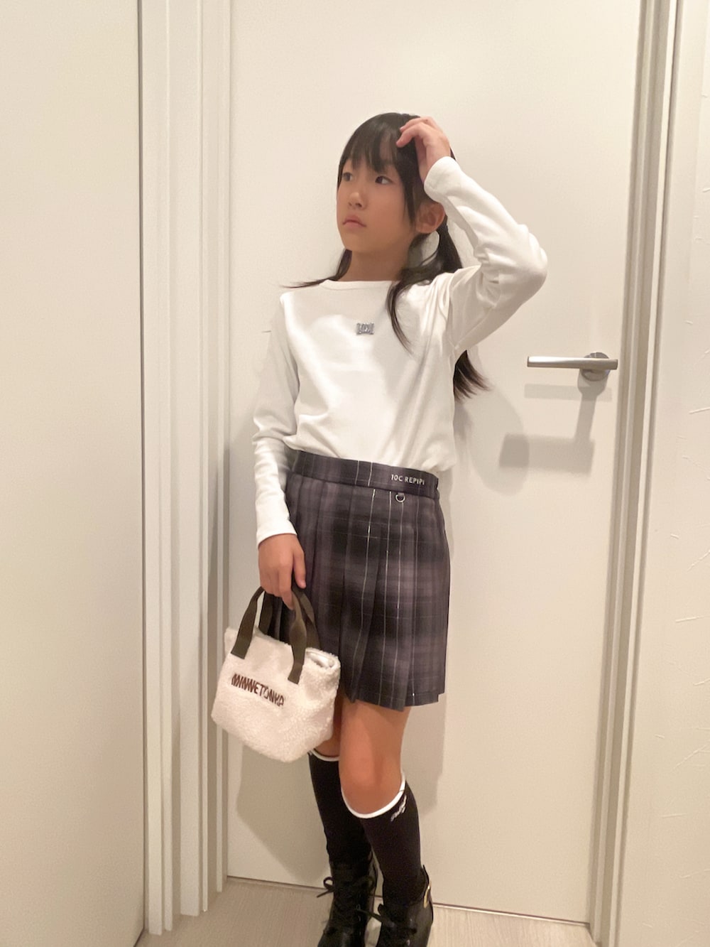 ホワイト系のトップス、ブラック系のスカート、ホワイト系のショルダーバッグを着用したキッズの秋コーディネートの2枚目の写真
