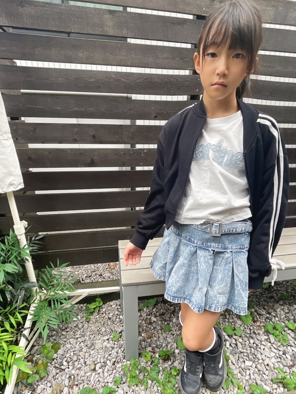 ブルー系のデニムスカート、ホワイト系のTシャツ/カットソー、ブラック系のセットアップを着用したキッズの秋コーディネートの2枚目の写真