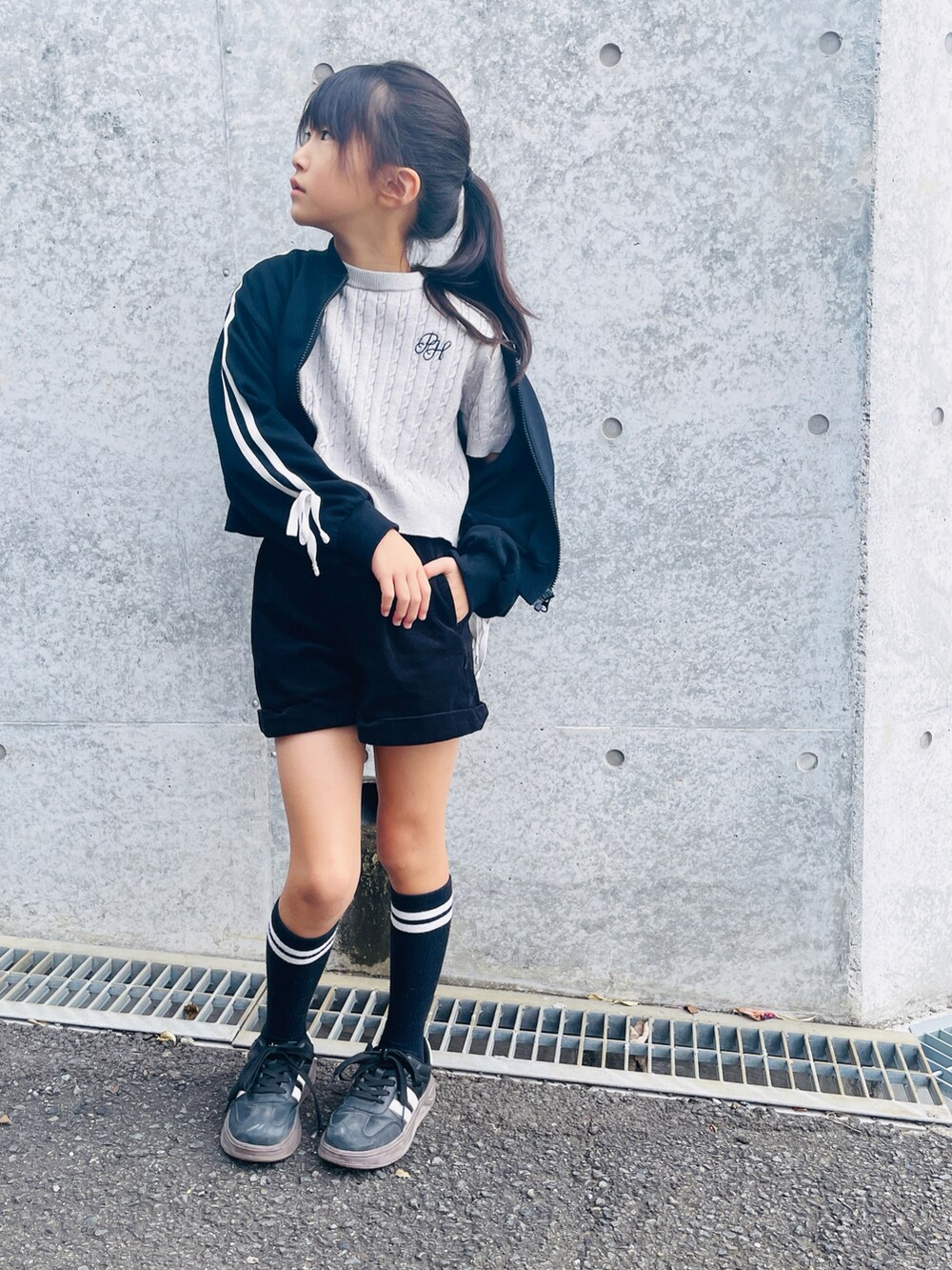 ブラック系のスニーカー、ブラック系のセットアップ、グレー系のTシャツ/カットソーを着用したキッズの秋コーディネートの2枚目の写真