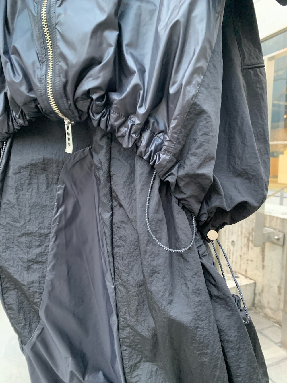 ブラック系のナイロンジャケット、ブラック系のジャンパースカート、ブラック系のサンダルを着用したレディースの冬コーディネートの5枚目の写真