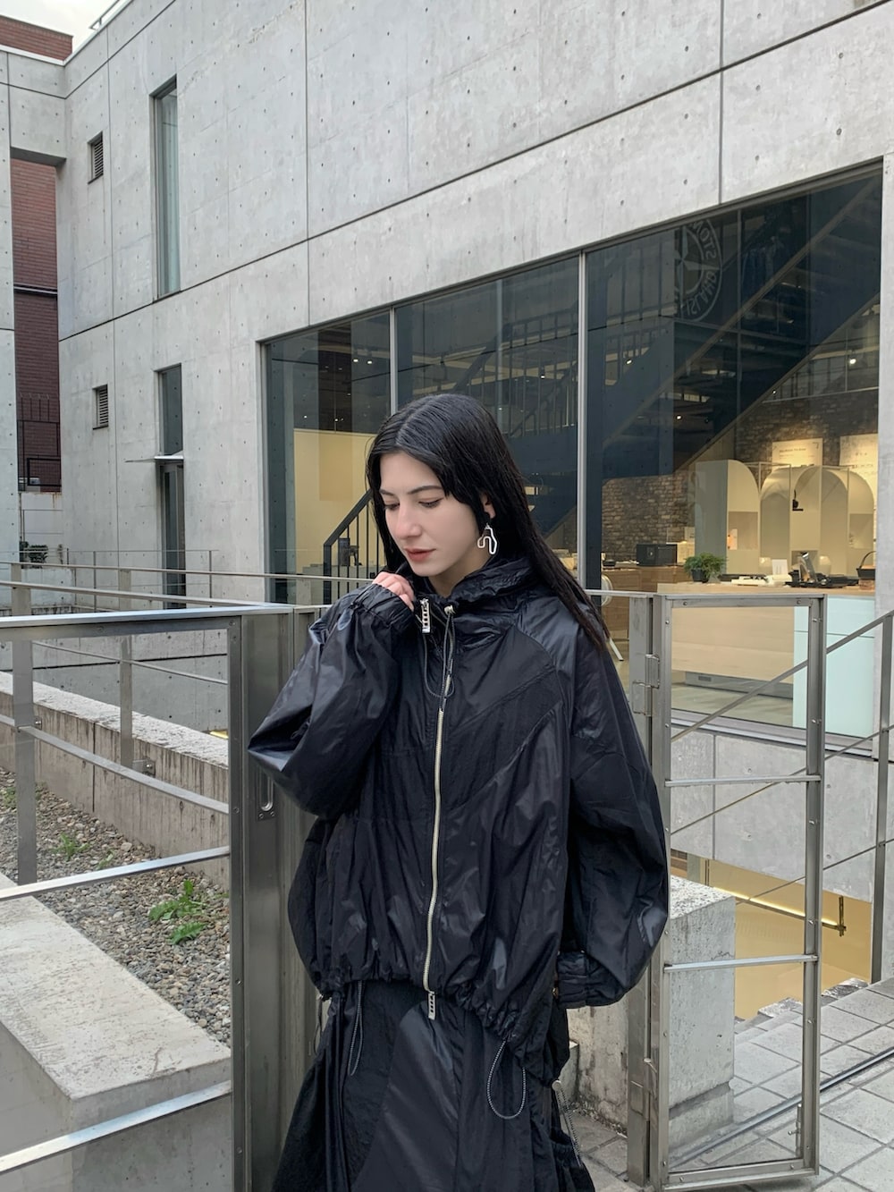 ブラック系のナイロンジャケット、ブラック系のジャンパースカート、ブラック系のサンダルを着用したレディースの冬コーディネートの2枚目の写真