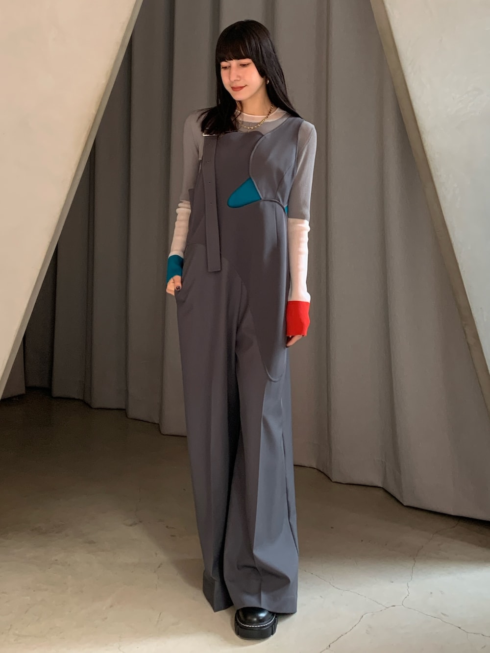 グレー系のつなぎ/オールインワン、オレンジ系のニット/セーターを着用したレディースの冬コーディネートの2枚目の写真