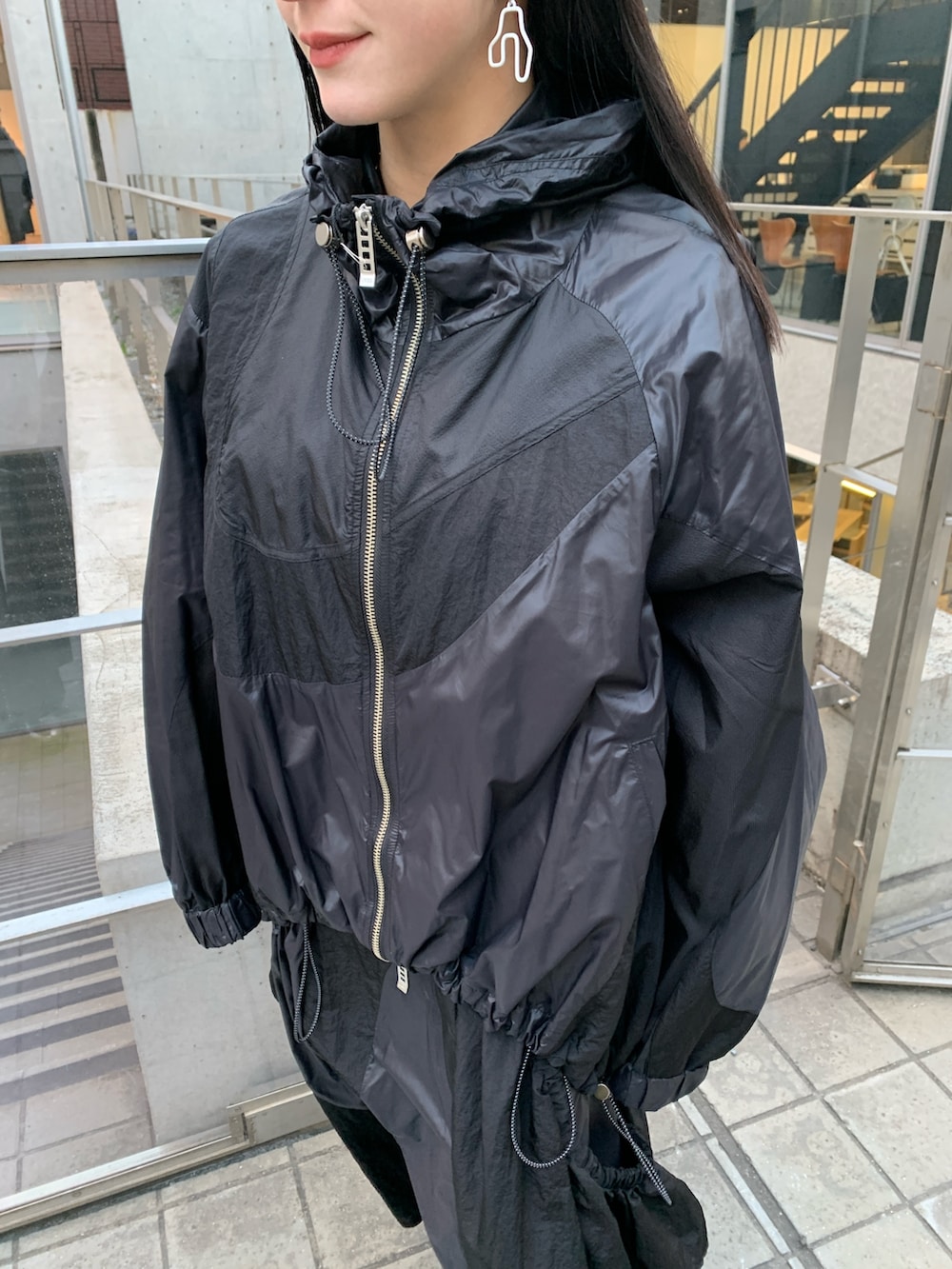 ブラック系のナイロンジャケット、ブラック系のジャンパースカート、ブラック系のサンダルを着用したレディースの冬コーディネートの4枚目の写真