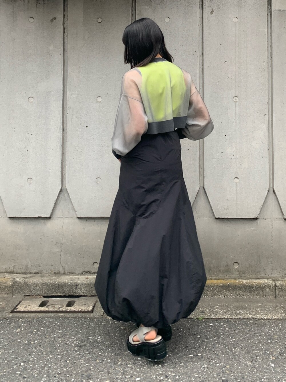 グレー系のカーディガン/ボレロ、イエロー系のタンクトップ、ブラック系のスカートを着用したレディースの春コーディネートの2枚目の写真